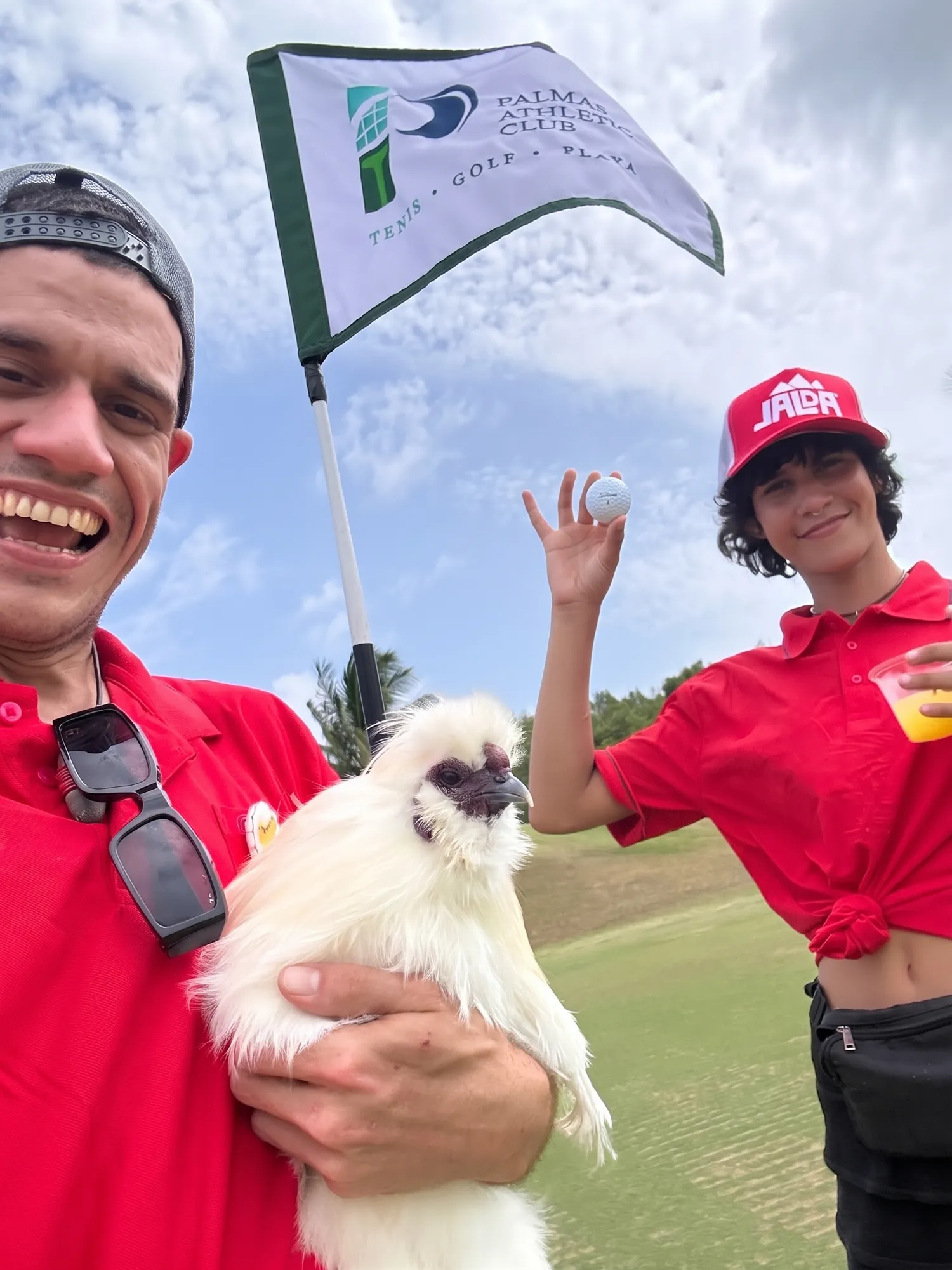 Armando de punto.pio con una gallina Silkie junto al banderín del Palmas Athletic Club